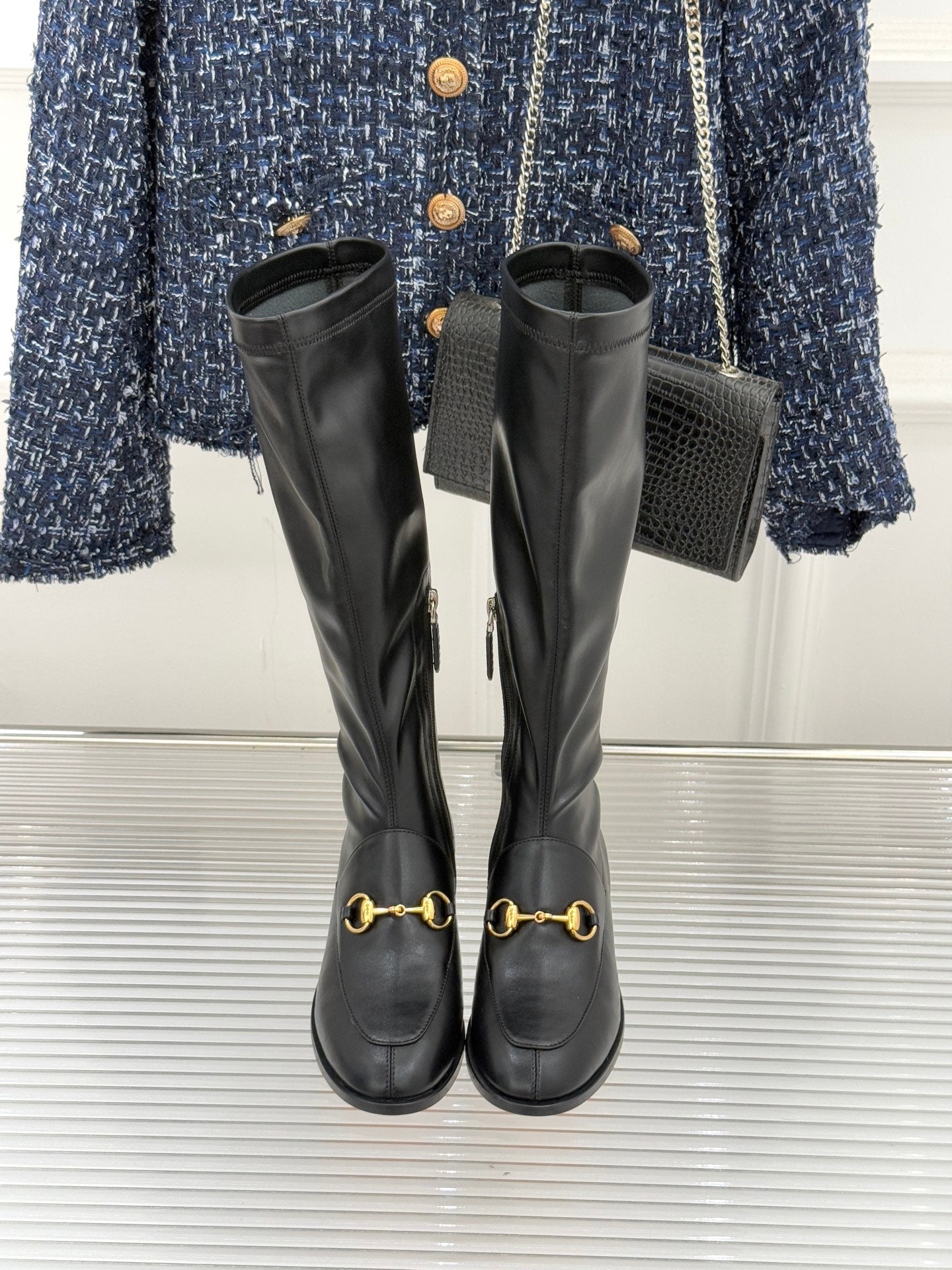 Black leather knee-high boots with gold horsebit straps and pull-tab zips