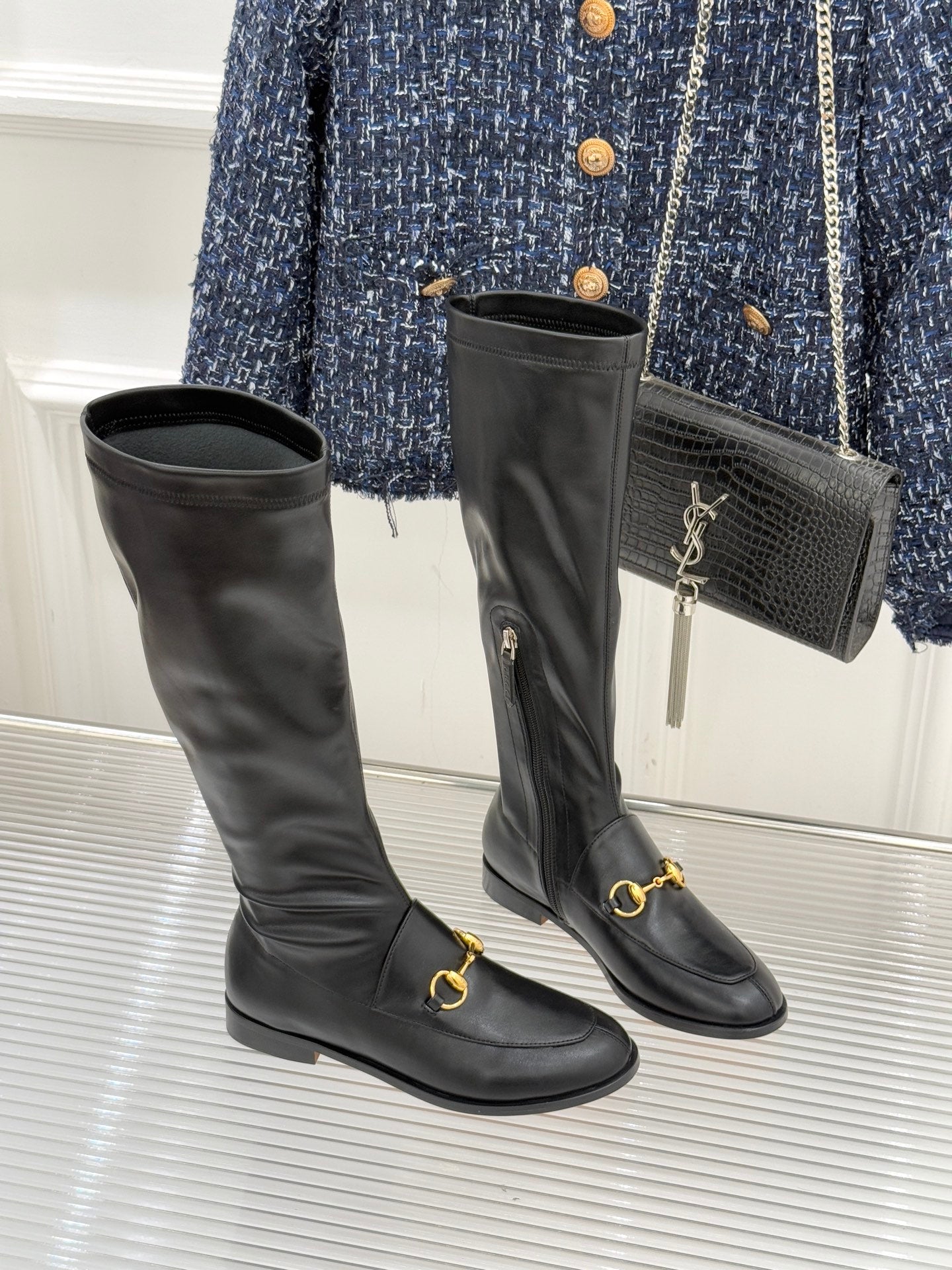 Black leather knee-high boots with gold horsebit straps and side zipper