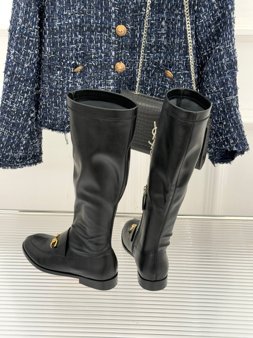 Black leather knee-high boots with gold horsebit detail and stacked heel