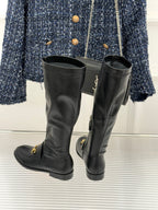 Black leather knee-high boots with gold horsebit detail and stacked heel