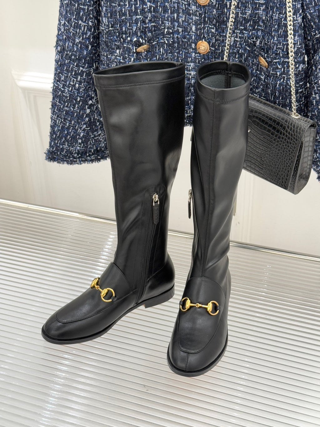 Black leather boots pair with gold horsebit accents and long side zipper detail