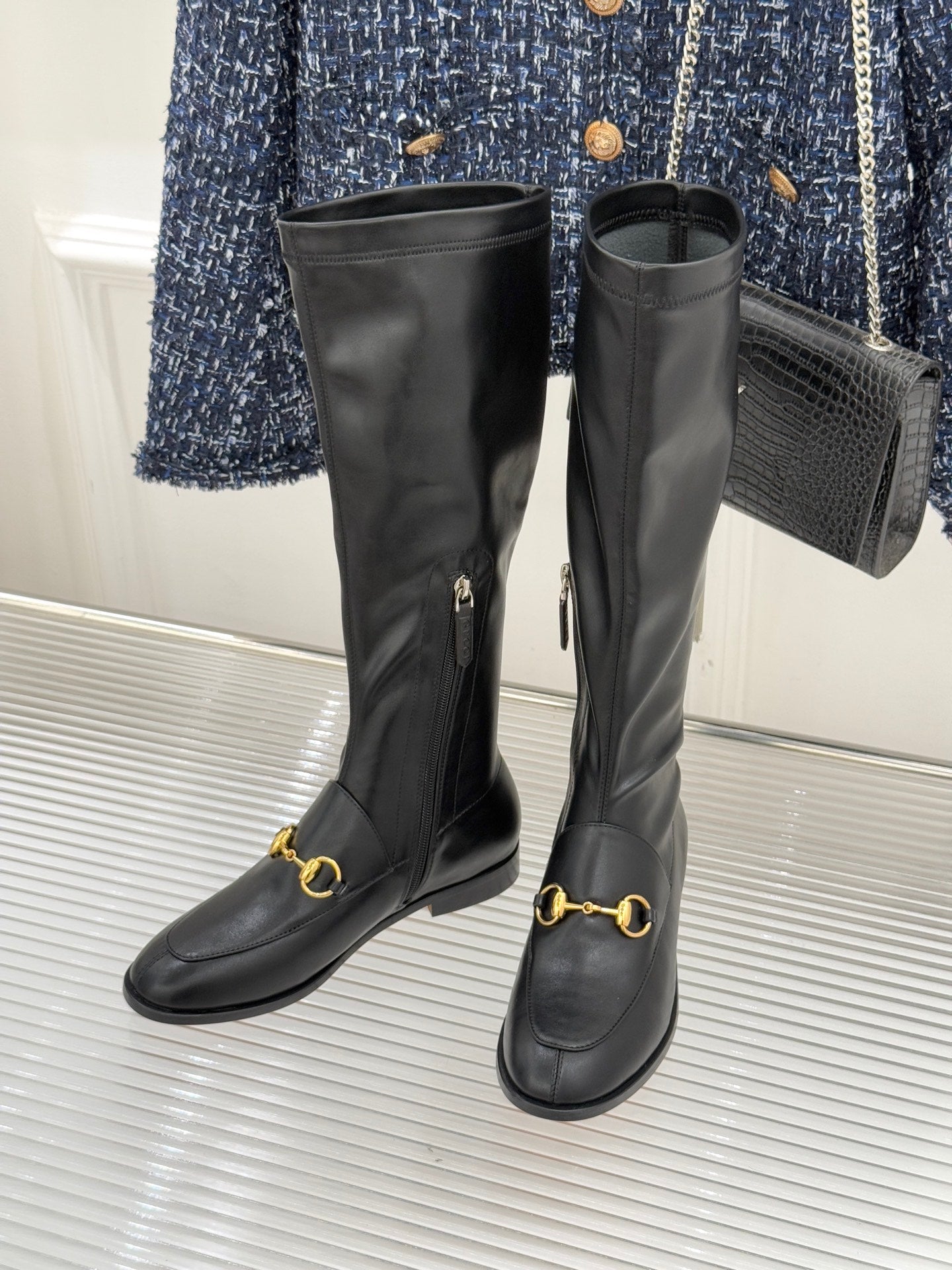 Black leather boots pair with gold horsebit accents and long side zipper detail