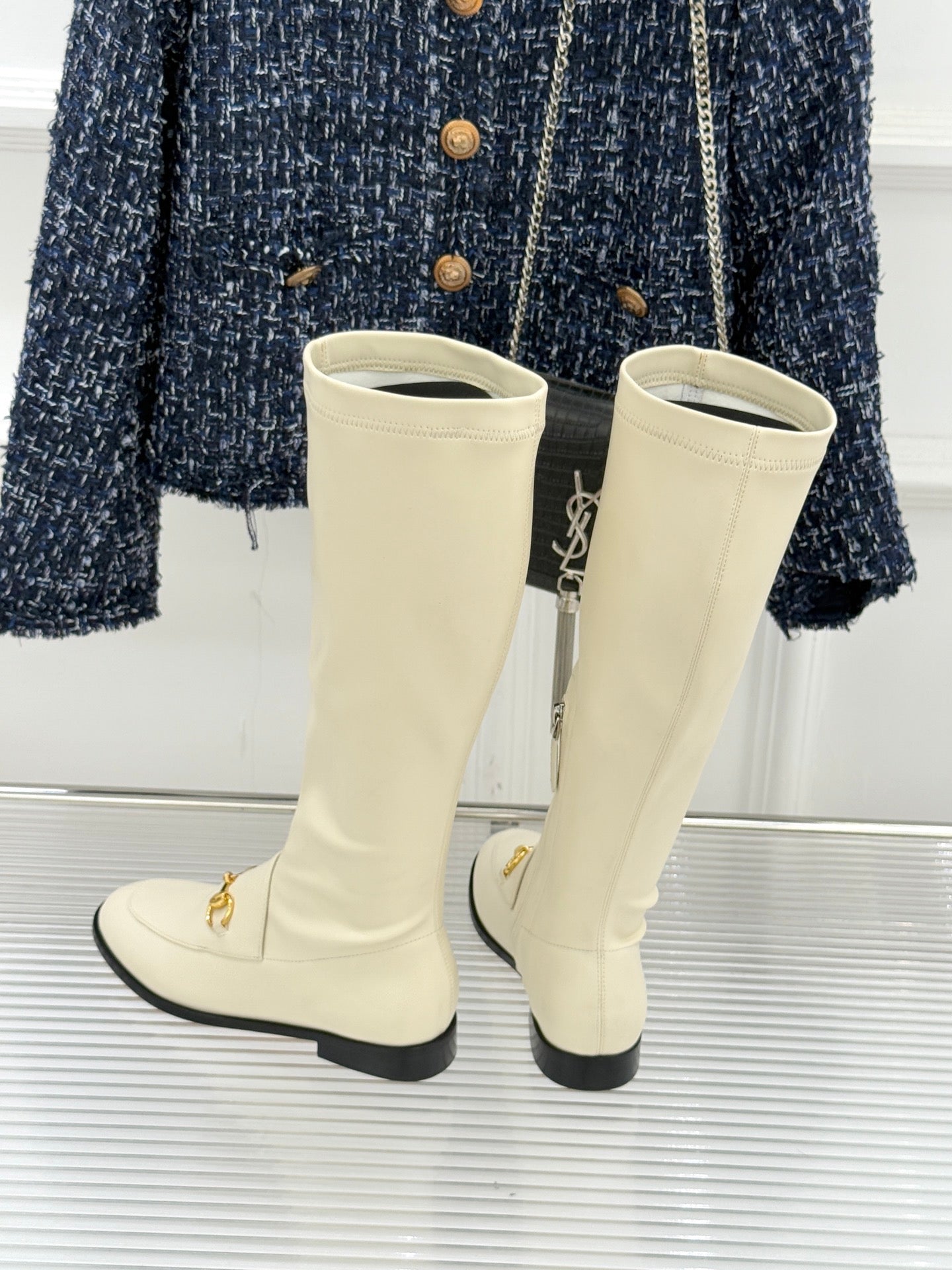 Women's off-white knee-high boots with gold zipper pull and black sole trim