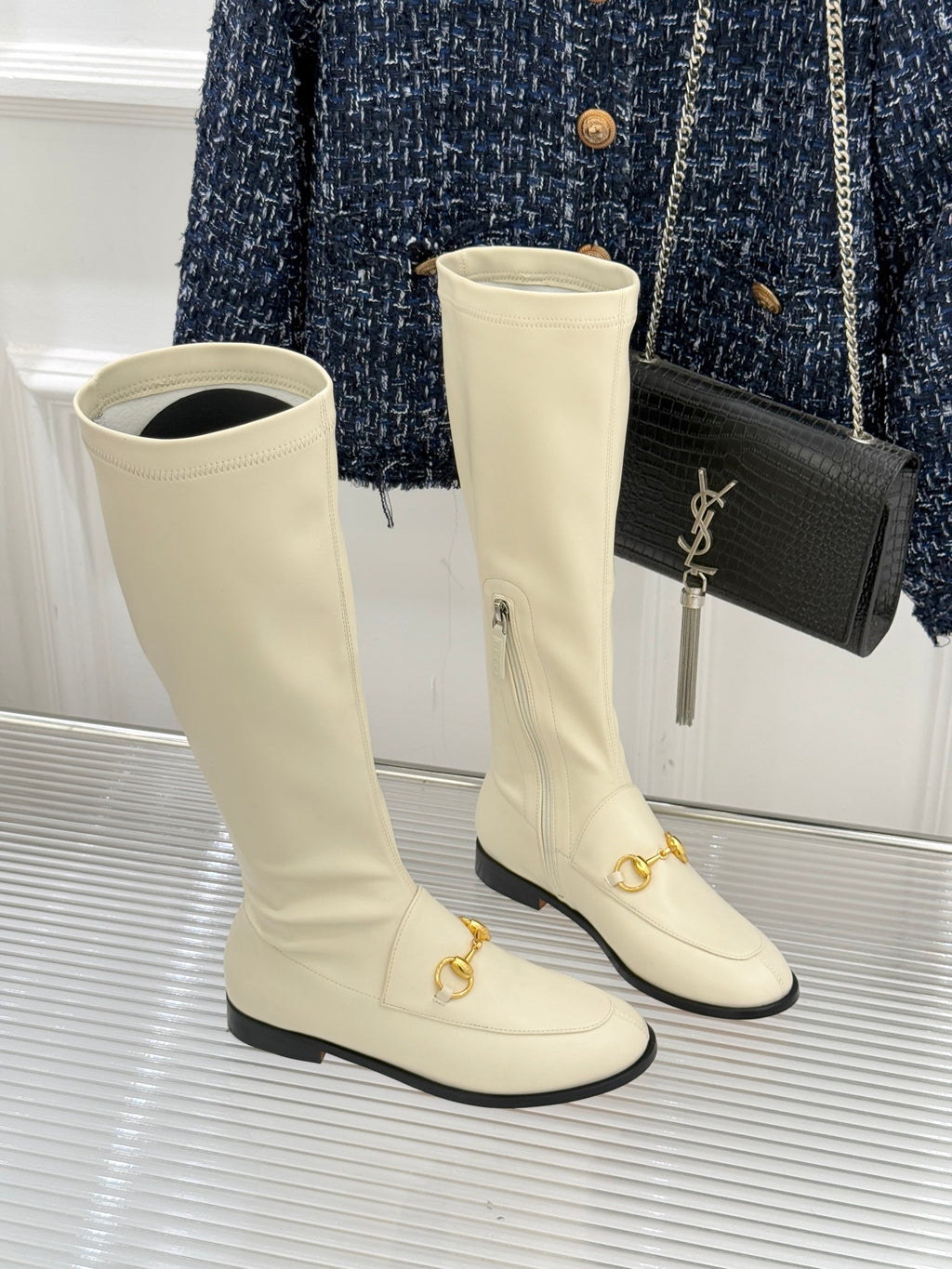Women's off-white knee-high boots with gold horsebit detail and black sole trim