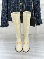 Women's off-white knee-high boots, front view, gold hardware on toes and black soles