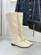 Women's off-white knee-high boots with gold buckle detail and black sole trim