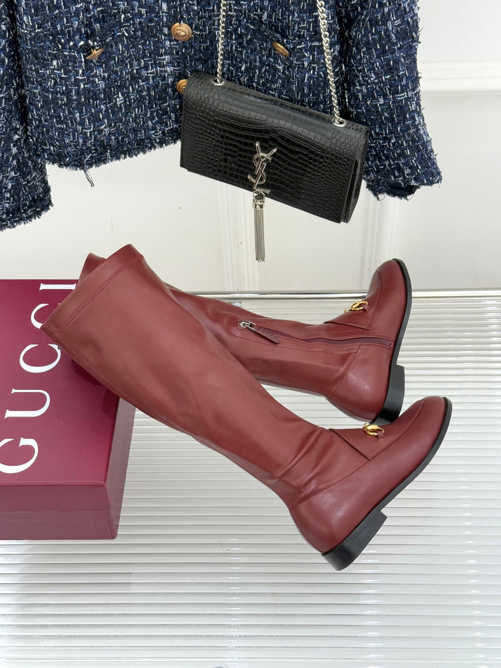 Maroon knee-high leather boots with gold horsebit bar detail and low block heel