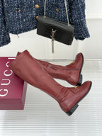 Maroon knee-high leather boots with gold horsebit bar detail and low block heel