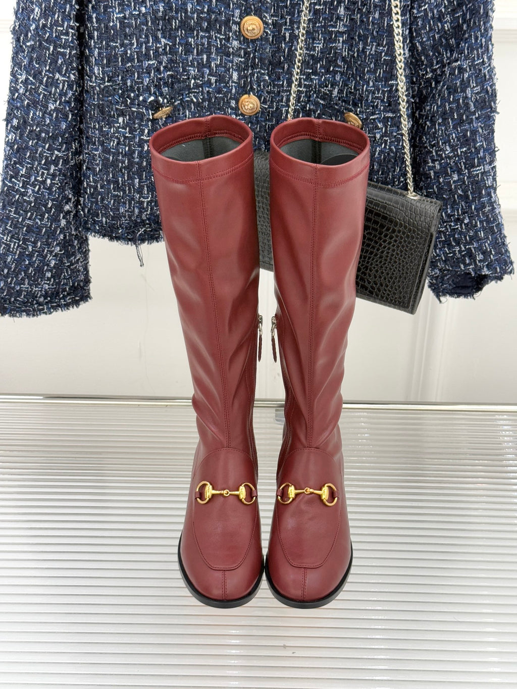 Maroon knee-high leather boots with gold horsebit accents, side seams, and block heels