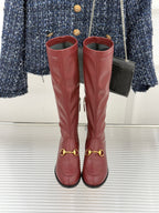 Maroon knee-high leather boots with gold horsebit accents, side seams, and block heels