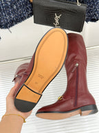 Maroon knee-high leather boots showing sole with Gucci logo and gold horsebit trim