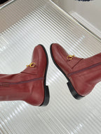Maroon slip-on knee-high boots with gold horsebit bar detail and rounded toe