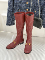 Maroon knee-high leather boots with gold horsebit buckle detail and block heel