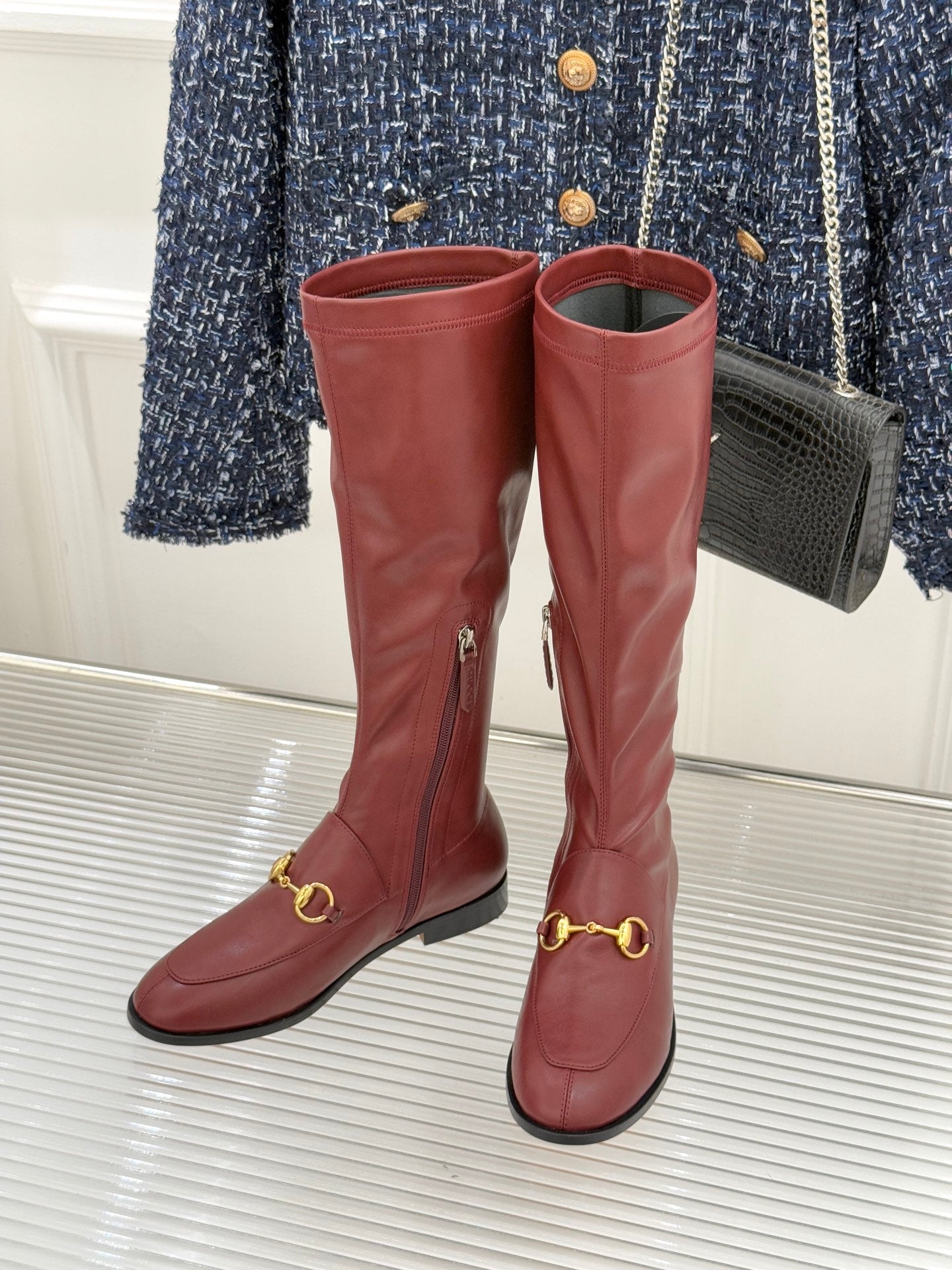 Maroon knee-high leather boots with gold horsebit buckle detail and block heel