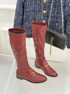 Maroon knee-high leather boots with gold horsebit strap detail and low block heel