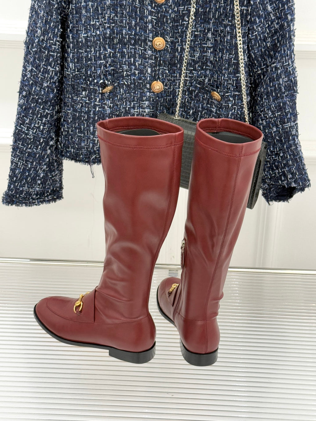 Maroon knee-high leather boots with gold horsebit detail and low block heel, pair view