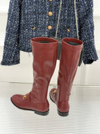Maroon knee-high leather boots with gold horsebit detail and low block heel, pair view