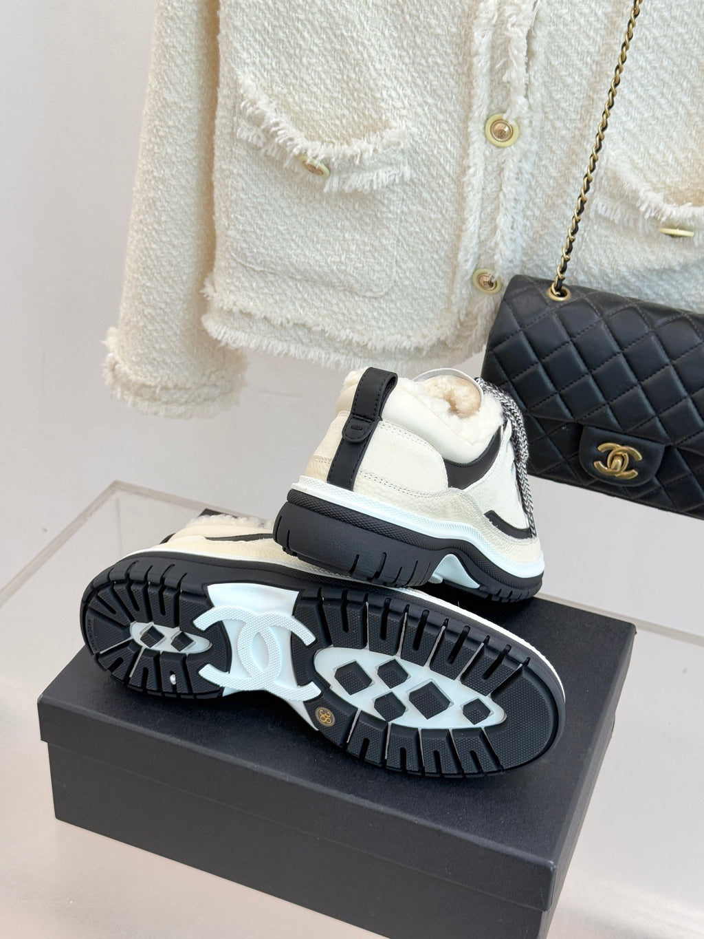Chanel sneakers showing outsole tread on a box, with white and black upper