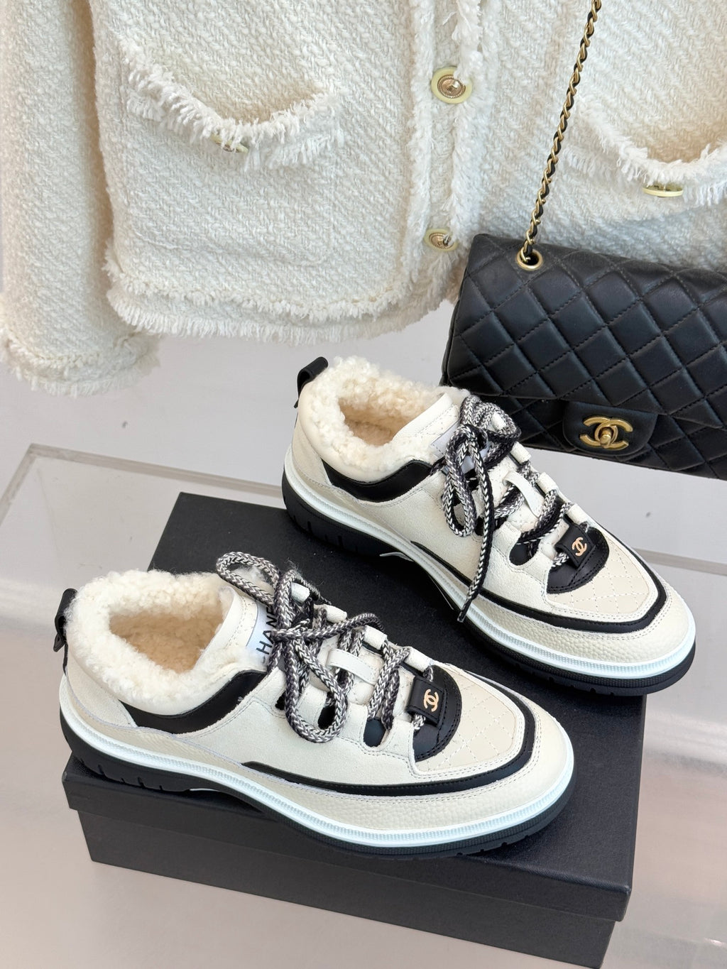 White and black Chanel sneakers on a box, showing rounded toe and lace-up eyelets