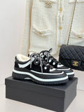 Black and white Chanel sneakers with shearling lining and chunky sole, laced up.