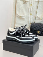 Black and white Chanel sneakers with shearling lining and chunky sole, laced up.