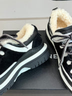 Black Chanel sneakers detail view: shearling-lined collar and white edge trim.