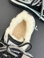 Black Chanel sneakers close-up with shearling interior and lace-up front.