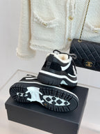 Black Chanel sneakers with shearling lining on display atop a dark box.