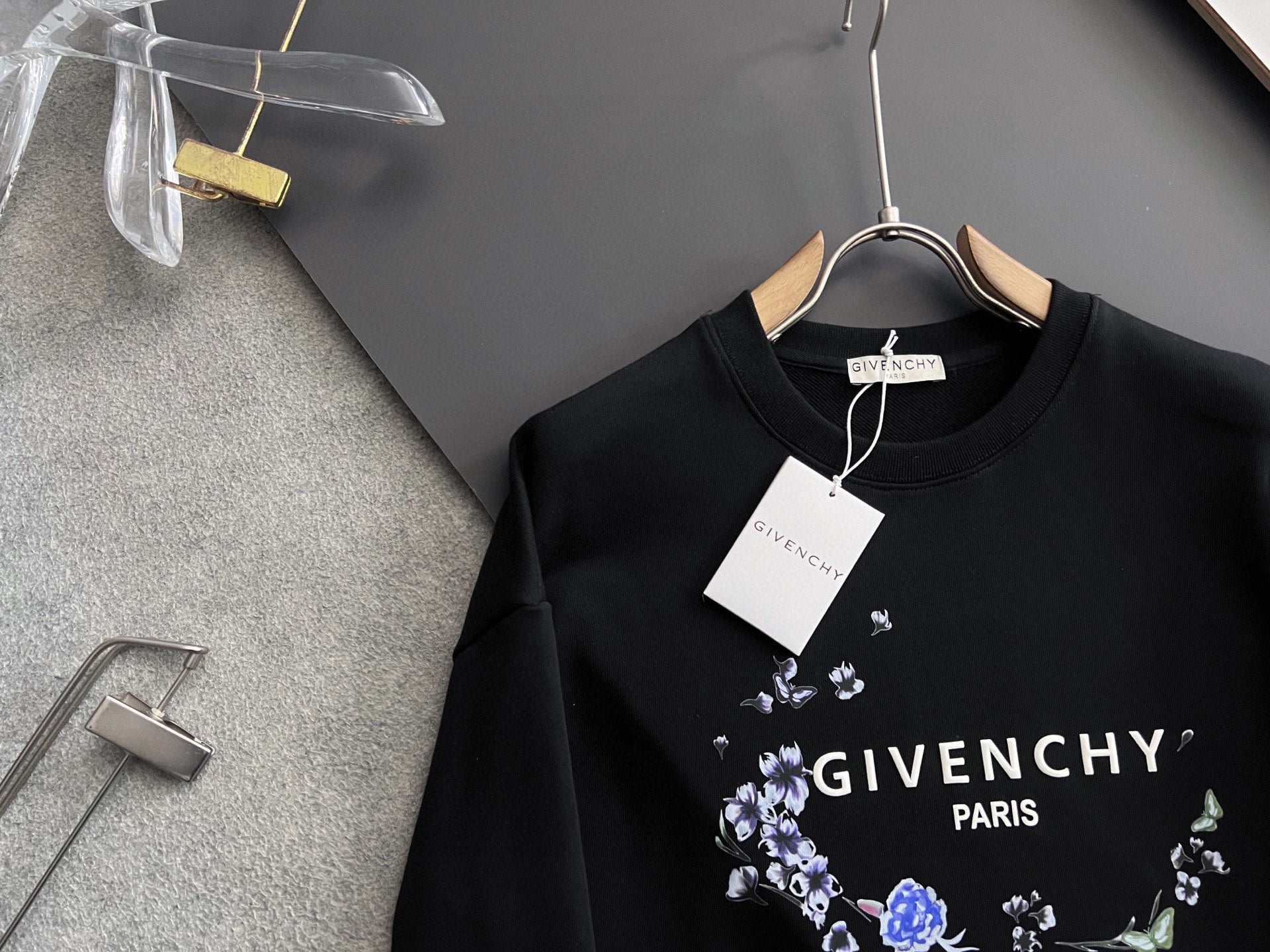Black crewneck sweatshirt with blue floral wreath logo and white “GIVENCHY PARIS”