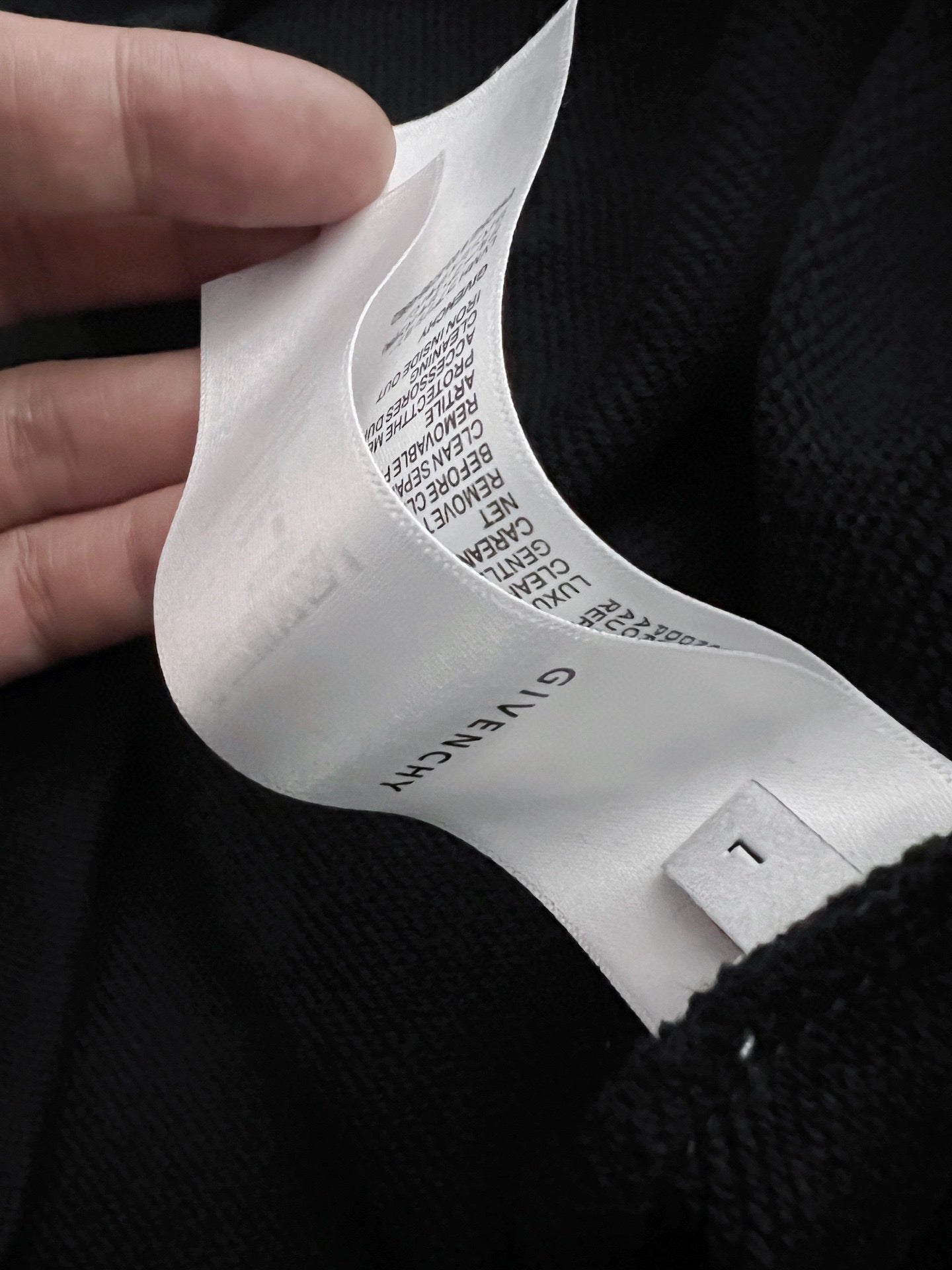 Inside neck of black sweatshirt showing care label and size tag