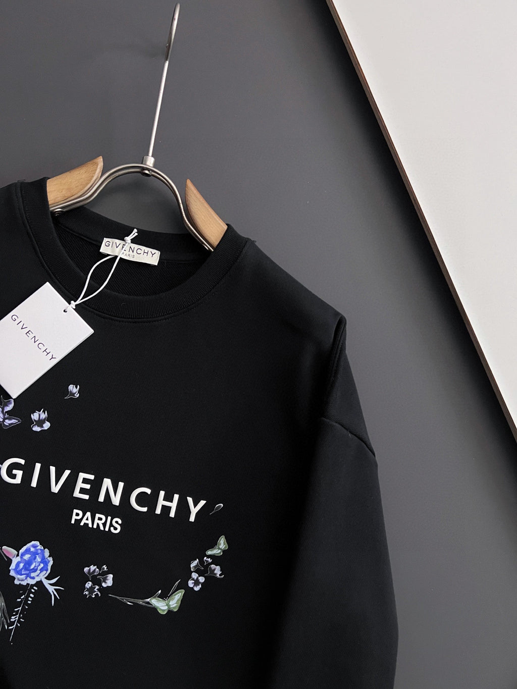 Black crewneck sweatshirt with blue floral graphic and “GIVENCHY” text on chest