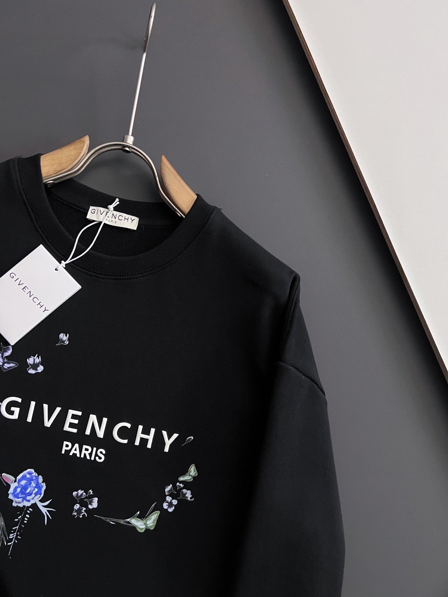 Black crewneck sweatshirt with blue floral graphic and “GIVENCHY” text on chest