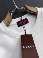 White crewneck sweatshirt neckline close-up with Gucci tags and collar seam