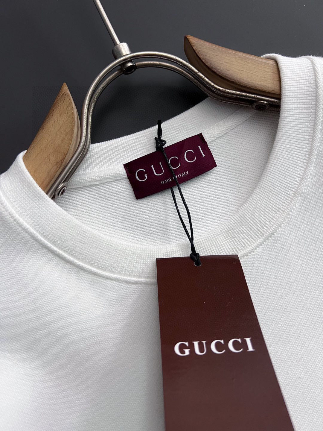 White crewneck sweatshirt neckline close-up with Gucci tags and collar seam