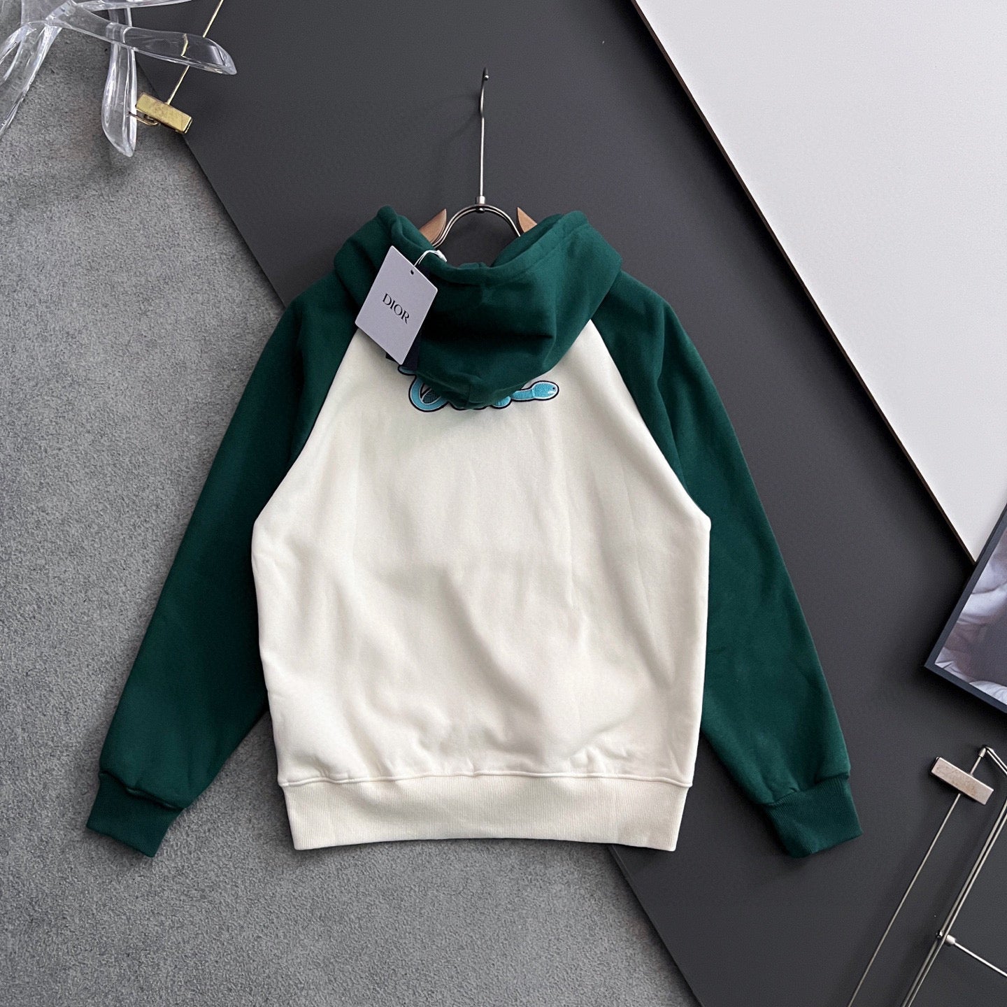 Green and white hoodie on hanger with hood and embroidered blue graphic on chest