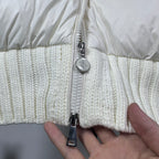 Long puffer jacket zipper close-up with silver pull and off-white knit hem