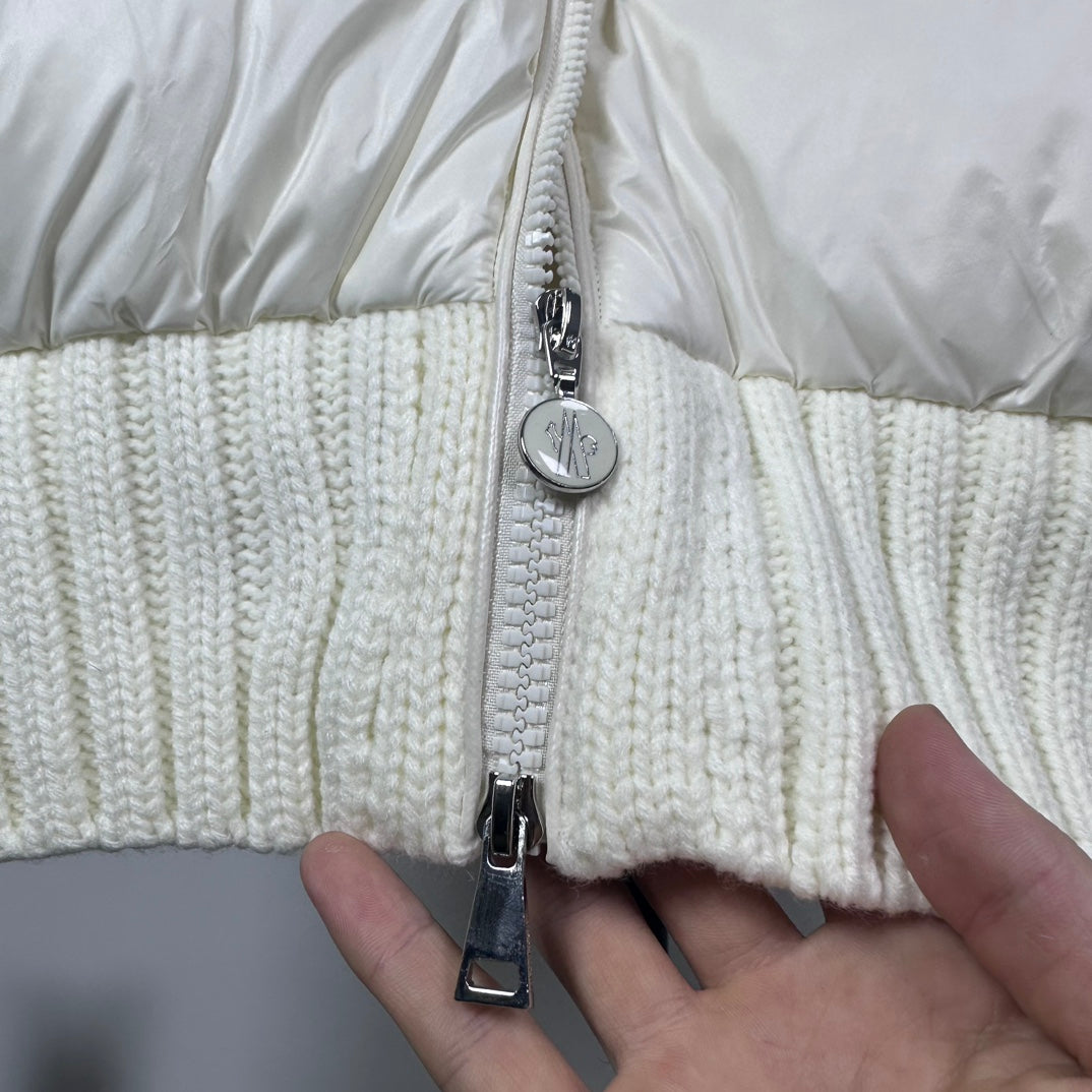 Long puffer jacket zipper close-up with silver pull and off-white knit hem