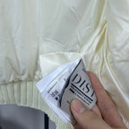 Long puffer jacket care label tag on off-white fabric near ribbed hem