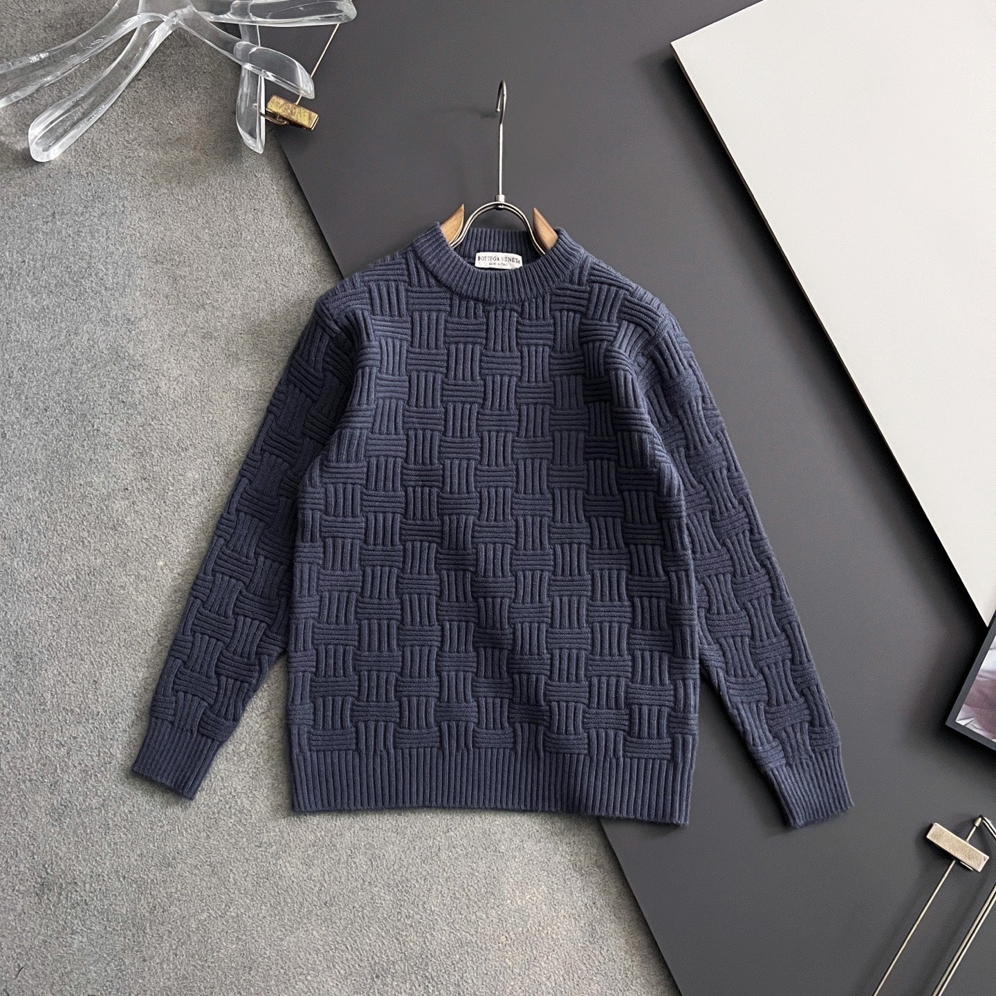 Dark blue textured knit sweater hanging on a hanger