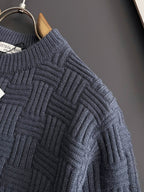 Dark blue knit sweater sleeve with raised square grid texture