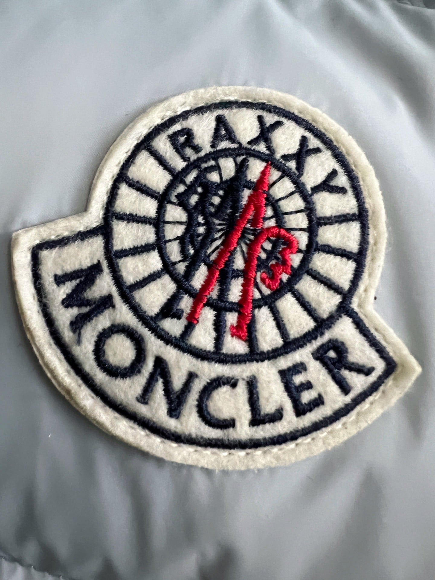 Round Moncler patch with AXIAL logo on light puffer jacket