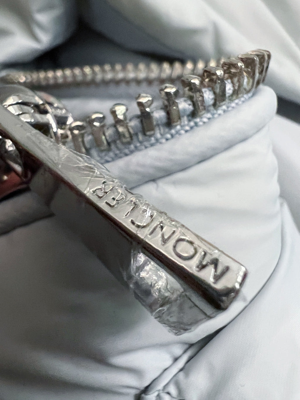 Metal front zipper on light Moncler puffer jacket with stitched detail