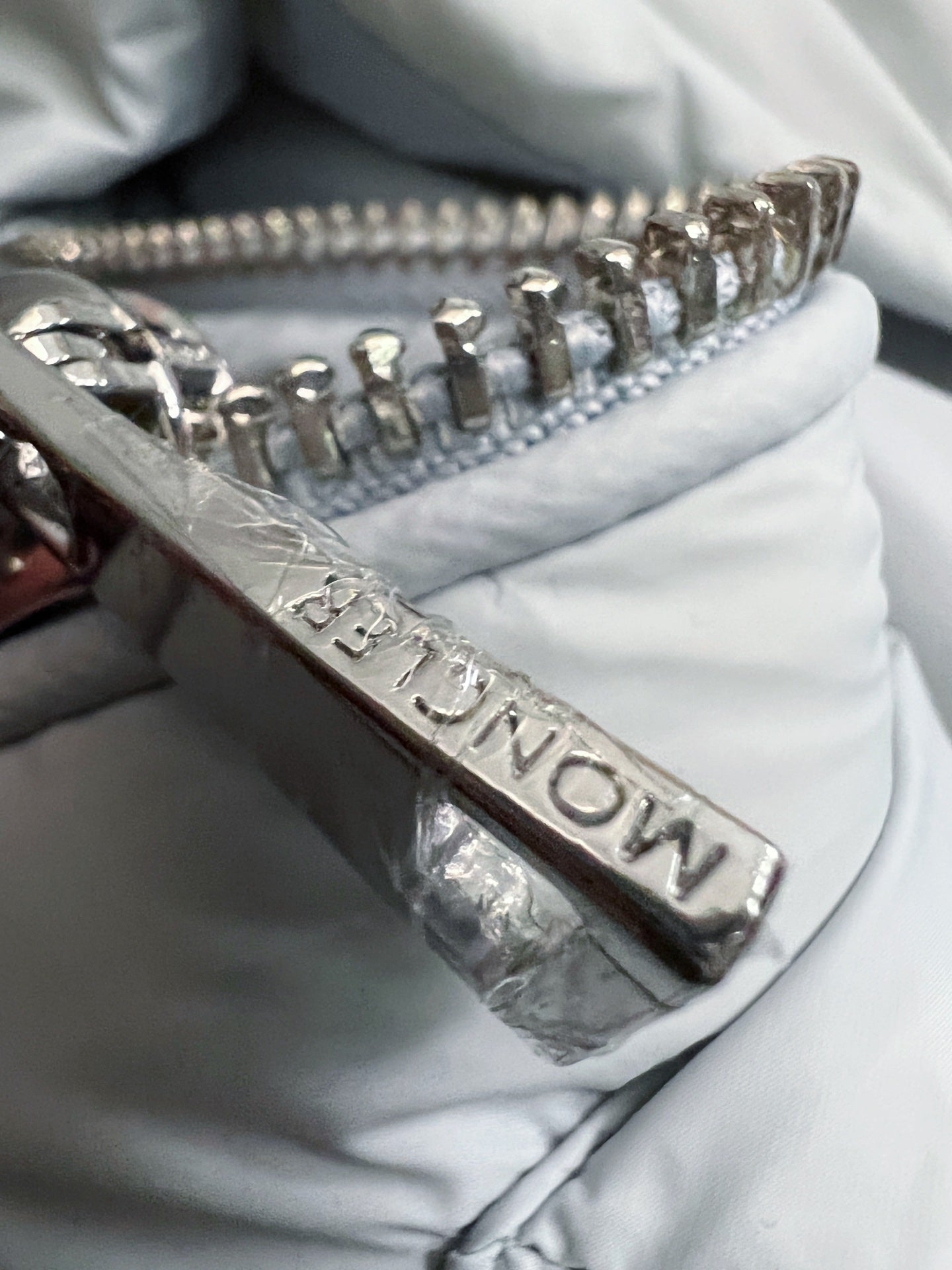 Metal front zipper on light Moncler puffer jacket with stitched detail