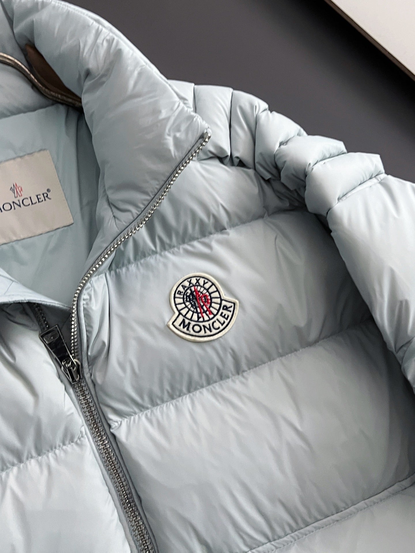 Moncler light puffer jacket with front zipper and round logo patch, close angle
