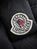 Moncler patch on black puffer fabric, red emblem with embroidered compass design
