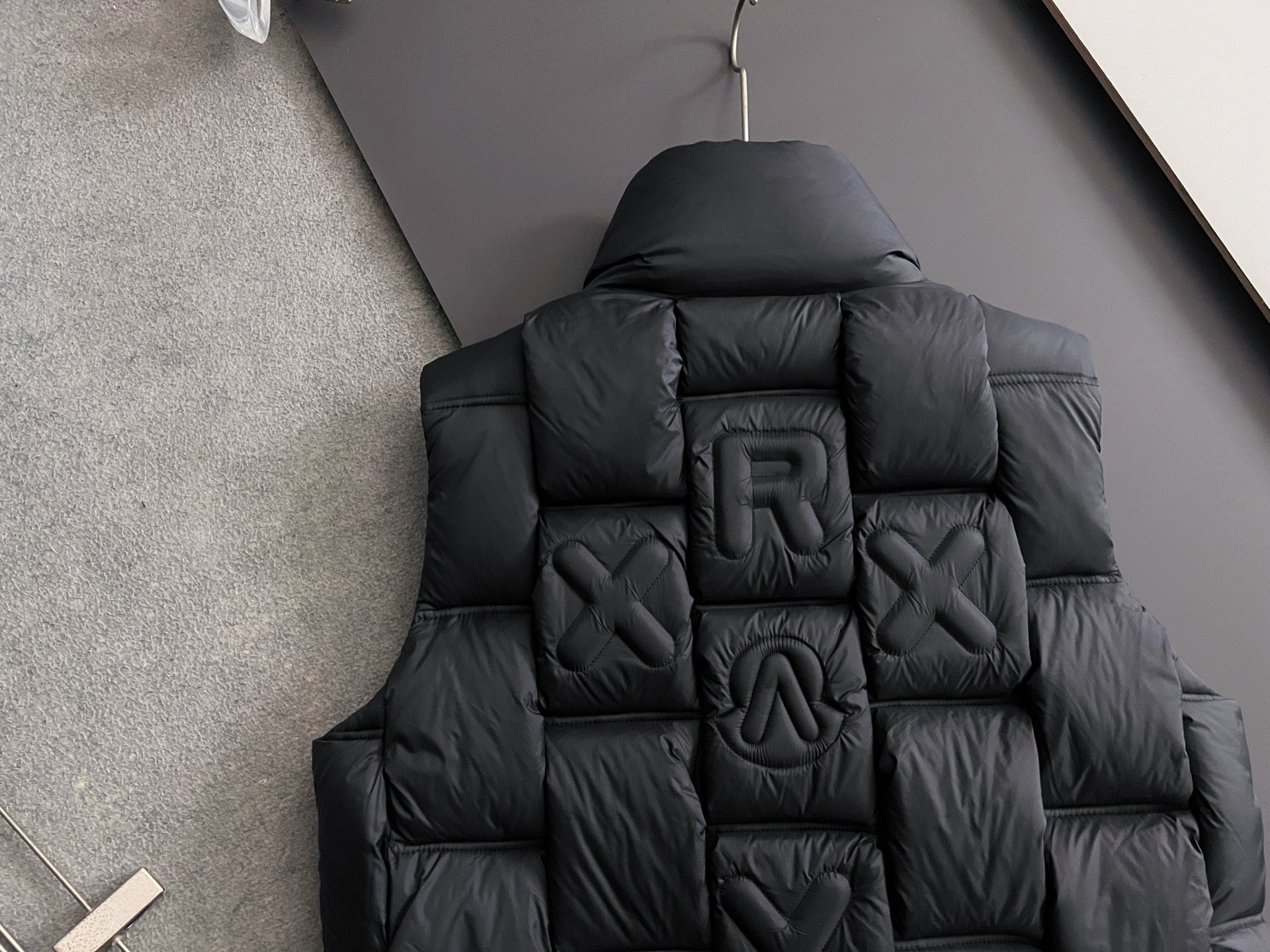 Black long puffer jacket back view with quilted 3D letters and hood
