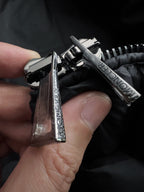 Metal snap and zipper pull on black puffer jacket, Moncler branding visible