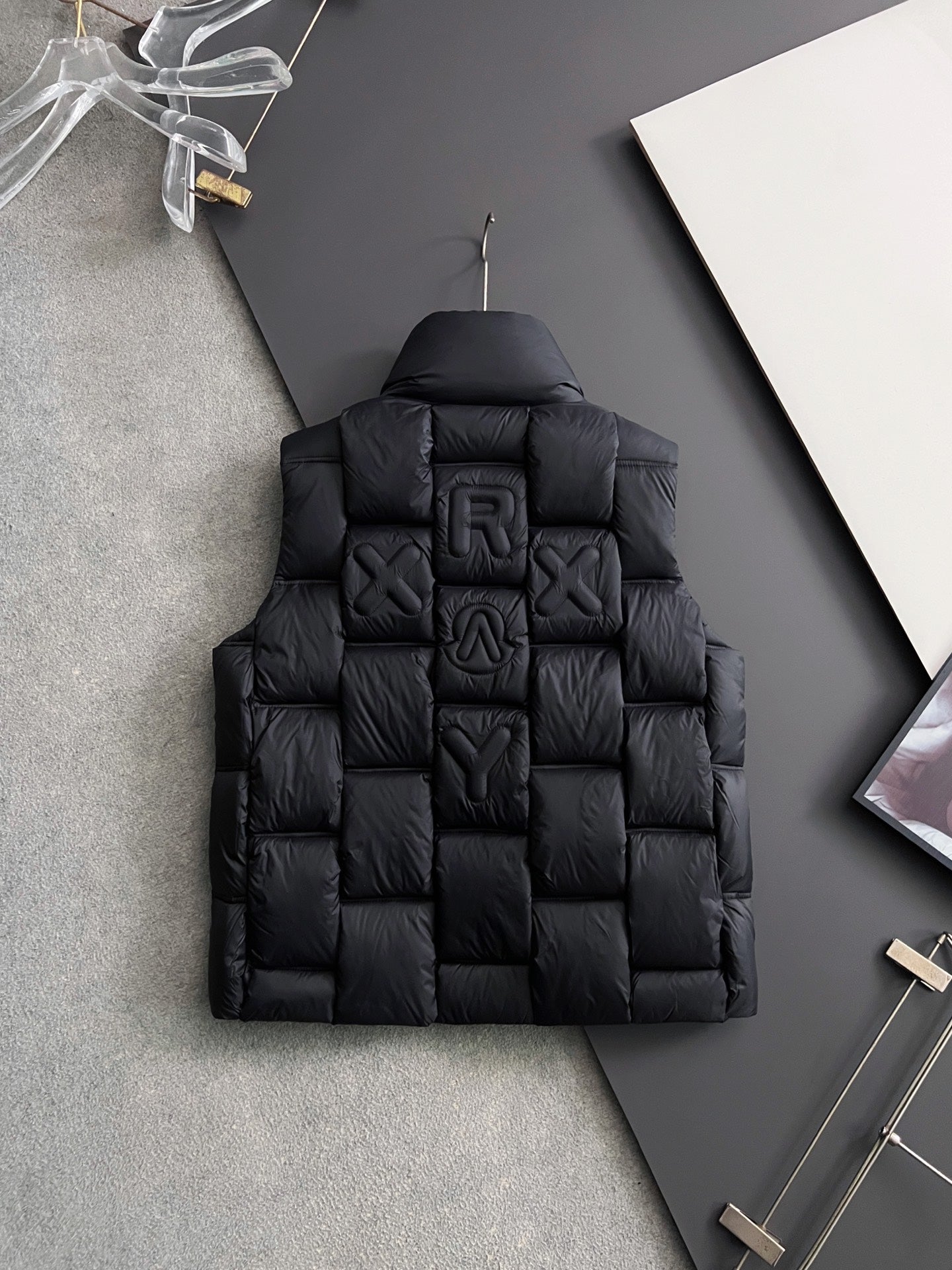 Black long puffer jacket back view with quilted lettering appliques and hood