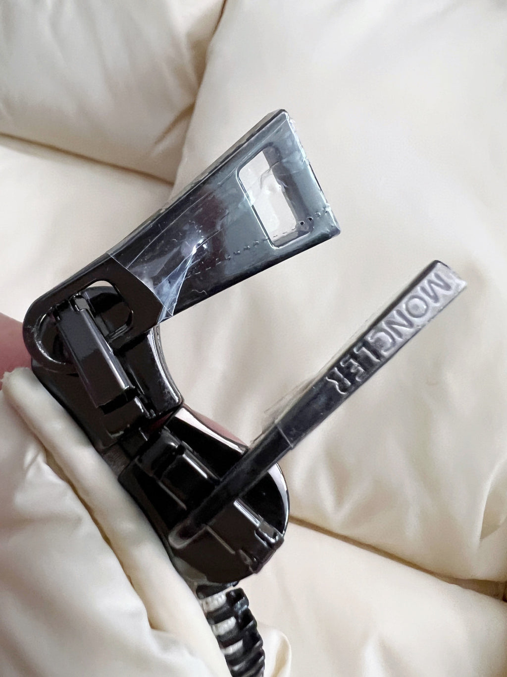 Cream puffer jacket zipper pull and black metal teeth with cord detail