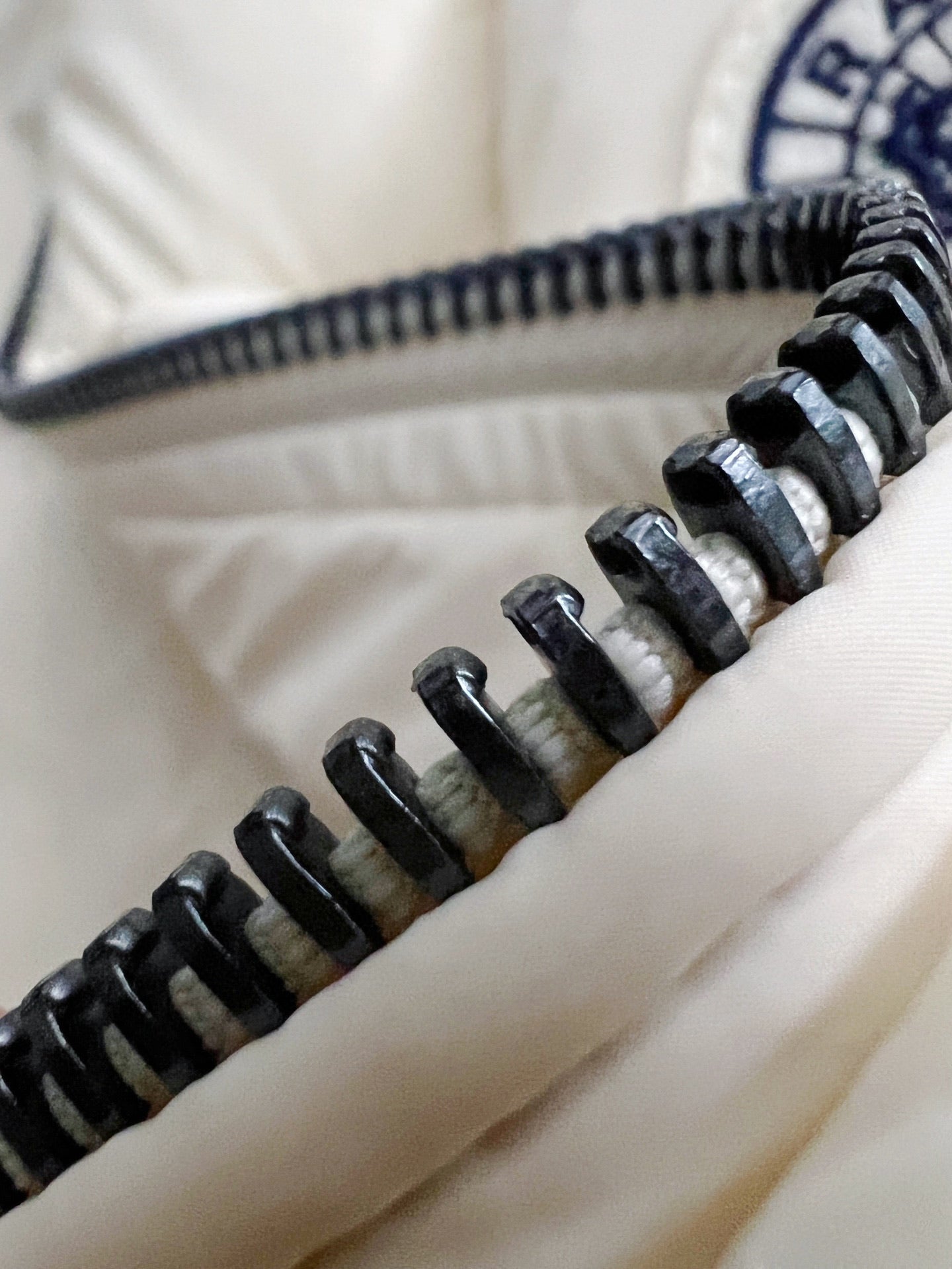 Close-up of cream puffer jacket zipper teeth and slider